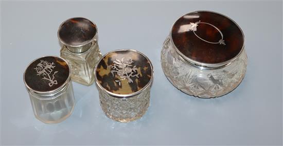 Three assorted silver and tortoiseshell pique mounted glass toilet jars and a similar salts bottle.